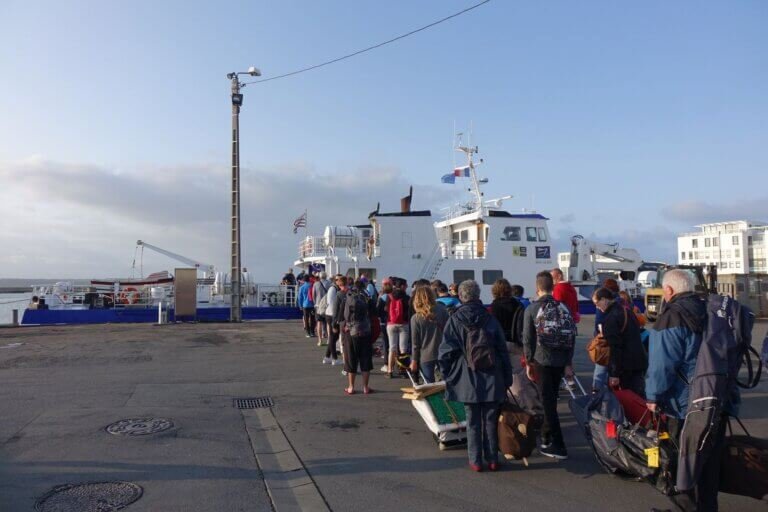 Groupe de personnes de dos, portant des bagages, accédant à un bateau