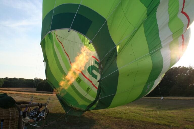 Montgolfière verte et blanche en train d'être gonflée à la flamme