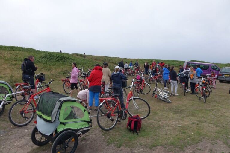 Rassemblement de personnes au milieu de vélos rouges, dans une plaine herbue